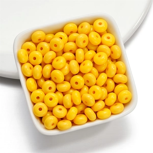 Macro detail of bright yellow acrylic disc beads in a white bowl for jewelry making
