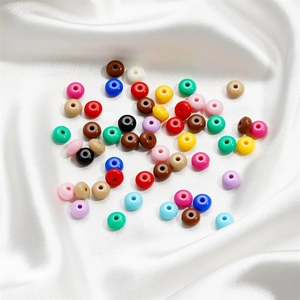 Macro view of 8mm acrylic candy colored wheel beads on white silk fabric for DIY jewelry
