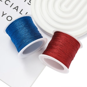 Primer plano de hilos de poliéster azul profundo y rojo oscuro en carretes para joyas