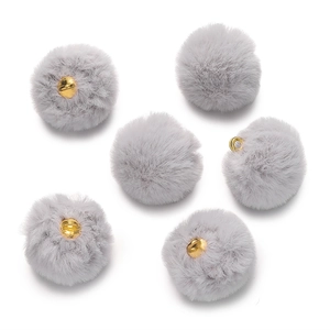 Macro shot of fluffy grey faux mink fur pom-pom pendants with gold metal rings for DIY jewelry