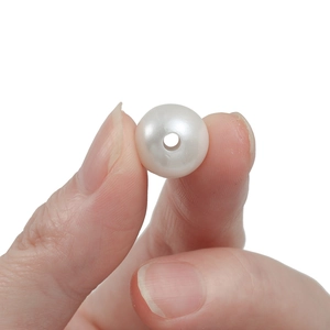 Macro view of a round white ABS faux pearl bead with a pre-drilled hole for DIY crafts