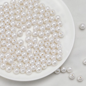 Macro shot of loose white ABS imitation pearls with pre-drilled holes for DIY jewelry making