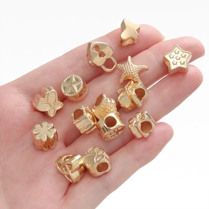 Gros plan de petites perles dorées DIY aux formes variées comme des étoiles dans une main