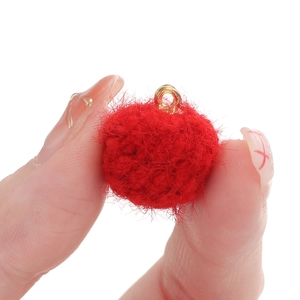 Détail d'un petit pendentif en fausse fourrure rouge avec anneau doré tenu par les doigts