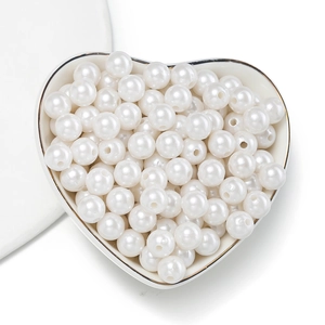 Detailed view of white ABS imitation pearls with pre-drilled holes in a heart-shaped tray