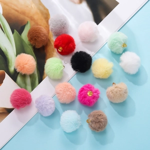 Macro shot of colorful plush pompom pendants with gold loops for DIY jewelry making
