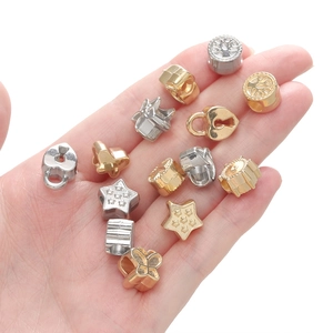 Perles de bijoux DIY dorées et argentées en formes d'étoile et cœur tenues en main