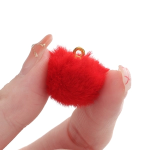Detailed view of a bright red faux mink fur pompom pendant with a golden metal ring