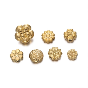 Macro shot of assorted golden stainless steel flower beads and clover spacers for DIY jewelry