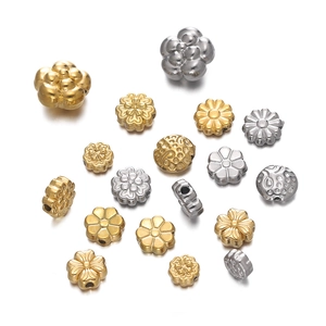Detailed macro of gold and silver flower-shaped stainless steel spacer beads with texture