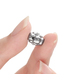 Silver stainless steel flower bead for jewelry DIY being held against white background