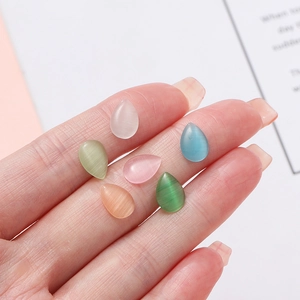 Hand holding six colorful teardrop cat eye glass beads for DIY jewelry making