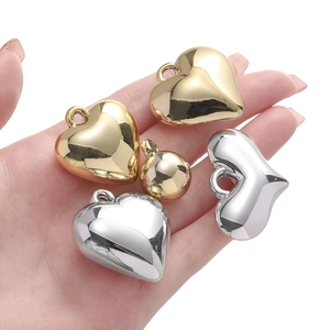 Dettaglio di ciondoli a cuore in metallo lucido oro e argento per la creazione di gioielli