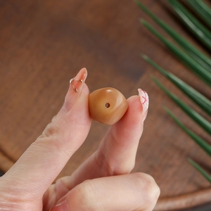 Close-up of a hand holding a brown carved bodhi root bead with a natural matte finish