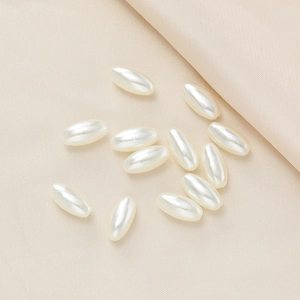 Macro shot of creamy white oval ABS pearls with high luster on textured fabric