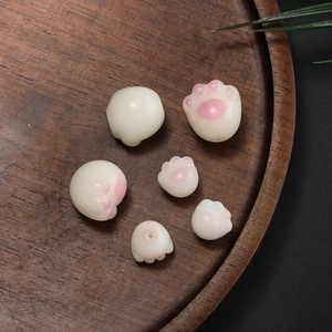 Makro-Detail von weißen und rosa Katzenpfoten-Perlen für DIY-Schmuck auf Holztablett