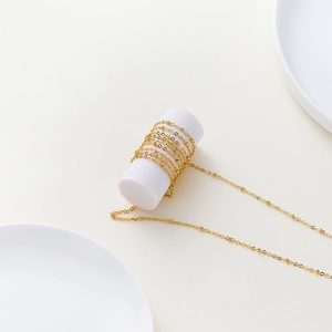 Polished gold beaded O-link chain wrapped on white display for DIY jewelry making