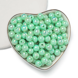 Dettaglio di perle acriliche verde menta con finitura AB in un piatto a cuore