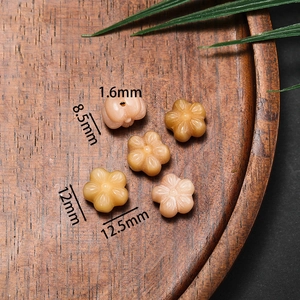 Vue macro de 5 perles de bodhi en forme de lotus orange sur un plateau en bois pour DIY