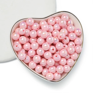 Perle in acrilico rosa con finitura AB cangiante in una ciotola di ceramica a cuore