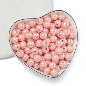 Dettaglio di perline acriliche rosa cangianti in una ciotola di porcellana a cuore