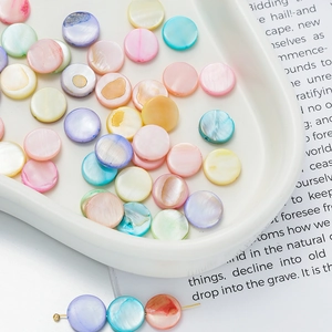 Macro shot of colorful shell beads for DIY jewelry making on white ceramic tray