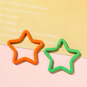 Close-up of orange and green star-shaped lacquered metal keyrings for DIY accessories