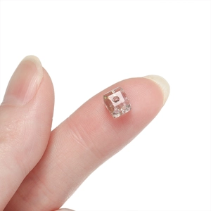 Macro shot of 6mm transparent square faceted glass crystal bead held on a fingertip
