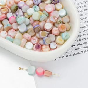 Macro shot of colorful iridescent square shell beads for DIY jewelry in a ceramic dish
