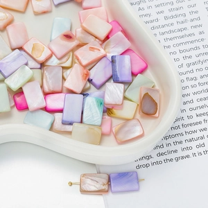 Close-up of colorful rectangle shell beads on white tray for DIY jewelry making