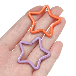 Star-shaped colorful metal key rings in orange and purple shown held by a hand