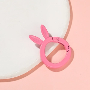 Pink matte rabbit-shaped alloy spring ring clip on a minimalist stone display base