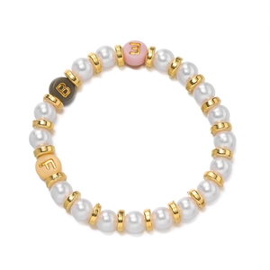 Dettaglio di bracciale con perle sintetiche, distanziali dorati e ciondoli con lettere