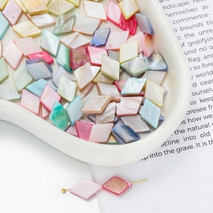 Macro shot of colorful diamond-shaped shell beads for DIY jewelry in a white tray