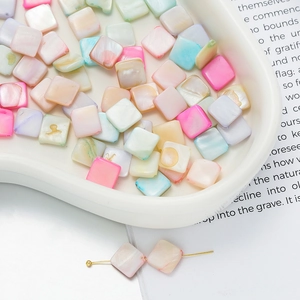 Macro view of colorful square shell beads in a ceramic bowl for DIY jewelry making