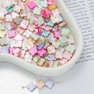 Close-up of colorful clover-shaped shell beads for DIY jewelry in a ceramic tray
