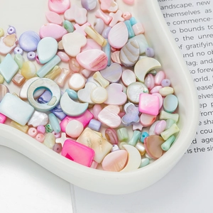 Close-up of pastel macaron shell beads in heart and moon shapes on a white tray