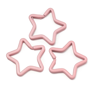 Close-up of three pink star-shaped metal key rings for DIY bag and doll accessories