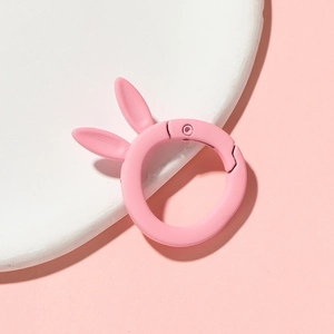 Close-up of a pink rabbit ear metal spring ring clasp with a matte painted finish