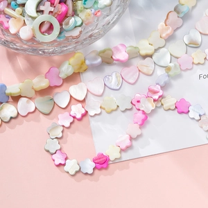 Close-up of pastel iridescent shell beads in heart and moon shapes for DIY jewelry