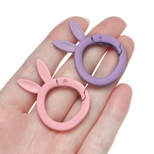 Close-up of matte pink and purple rabbit-shaped spring buckles for DIY keychains