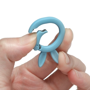 Close-up of light blue matte bunny-shaped spring ring buckle being opened by hand