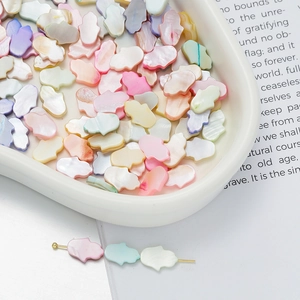 Macro shot of colorful shell Hamsa beads in a white bowl for DIY jewelry making