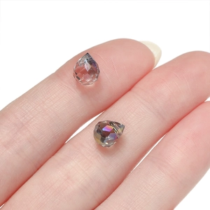 Close-up of teardrop faceted crystal beads with AB coating on a person's fingertip