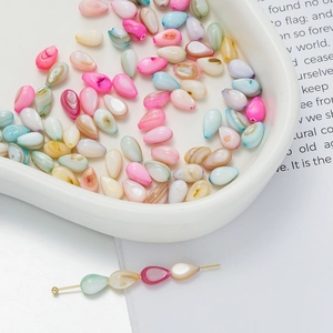 Macro shot of colorful pear-shaped shell beads for DIY jewelry making in a heart tray