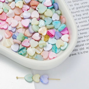 Macro shot of colorful heart-shaped shell beads for DIY jewelry in a white tray