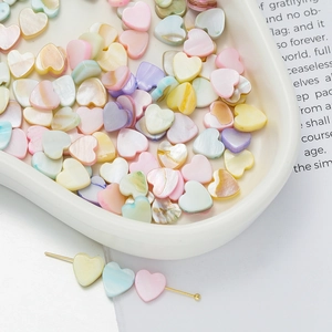 Macro shot of colorful heart shell beads for DIY jewelry making on white tray