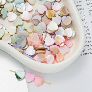Macro shot of colorful heart-shaped shell beads for DIY jewelry making in a white tray
