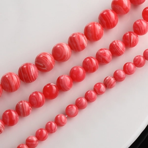 Macro shot of red and white striped agate beads showing various sizes and polished texture