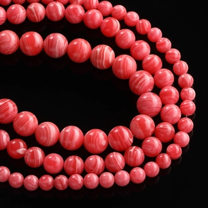Macro detail of red and pink striped agate beads with marble texture in various sizes